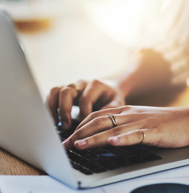 Closeup of a woman's hands on a laptop keyboard.